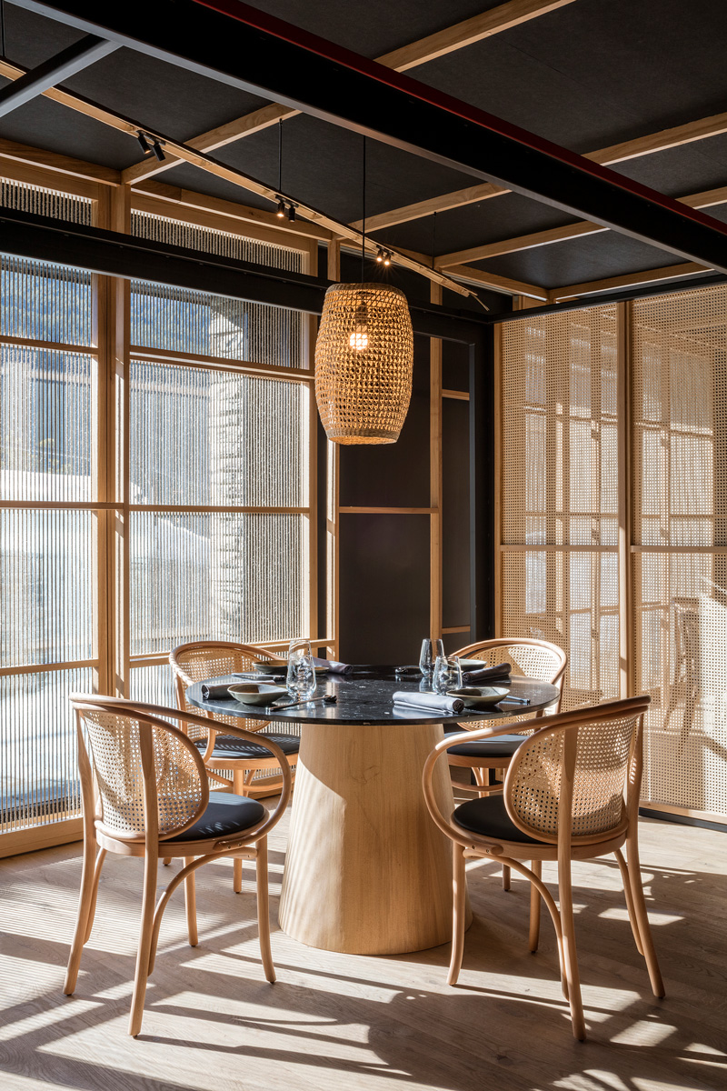 Vista del interiorismo del restaurante Kao Soldeu y el entramado de madera en techo, mamparas de madera y cuerda, sillas de Vergés y mesa de Pilar Líbano