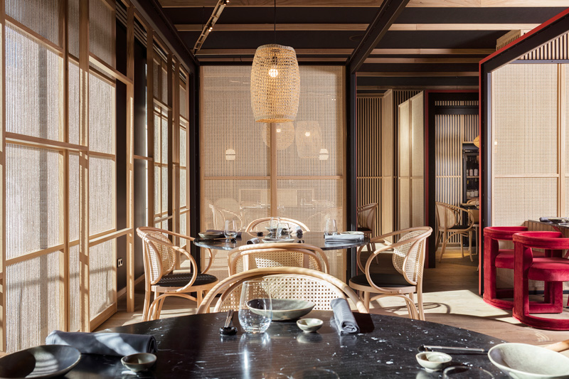 Vista del interiorismo de Pilar Libano para el restaurante Kao Soldeu, mesas, mamparas y celosías diseñadas por la interiorista, sillas de madera de Vergés y sillas tapizadas en terciopelo rojo