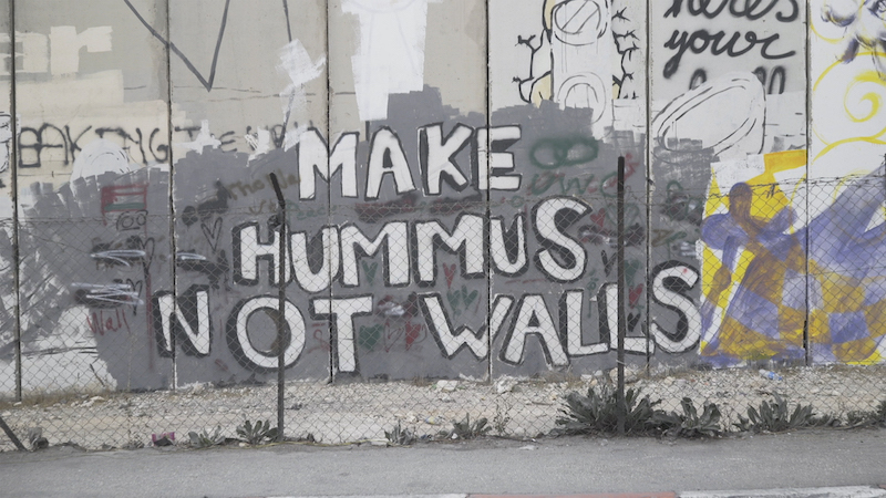 Pared de la ciudad de Belen en Palestina donde se lee el grafiti "MAKe HUMUS NOT WALLS"