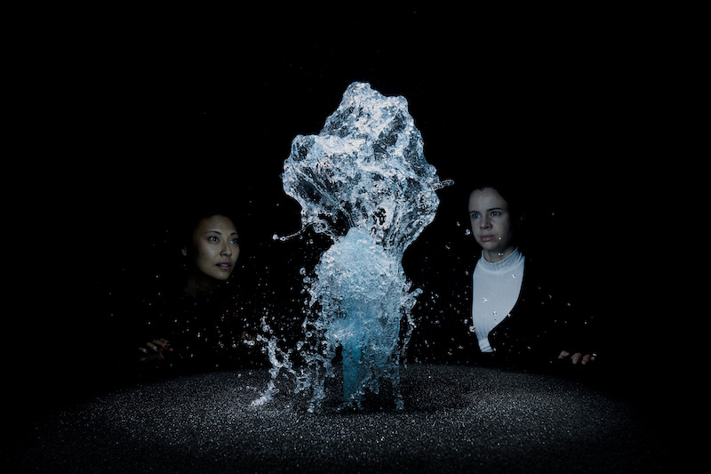Olafur Eliasson - chorro de gotas de agua iluminado con foco y dos personas mirando
