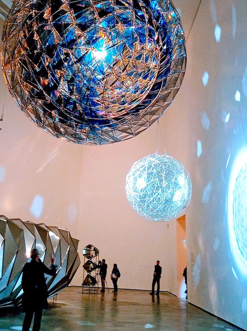 Olafur Eliasson - bolas gigantescas de espejos y vidrio colgando y con reflejos en las paredes