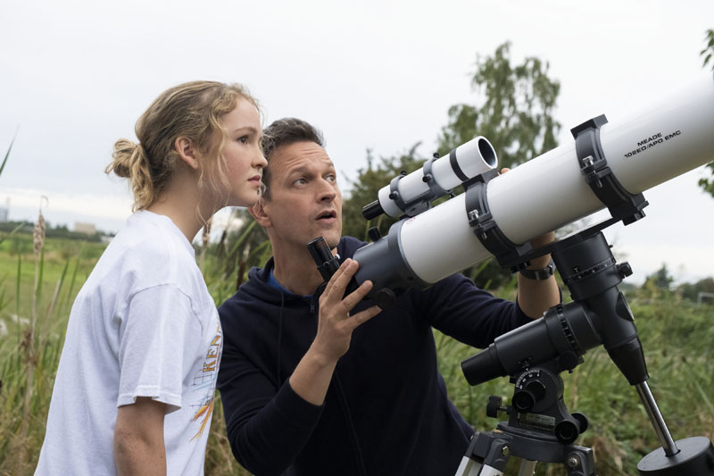 Away: un padre mirando por un telescopio con su hija.