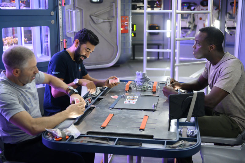Away: tres astronautas jugando a las cartas.