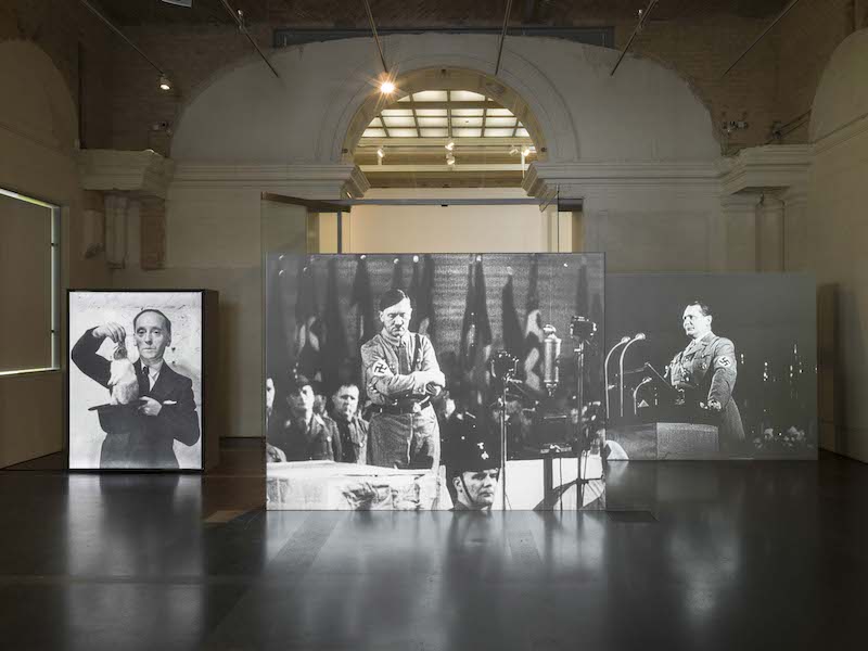 John Heartfield. Vista de la exposición John Heartfield - Photographie plus Dynamit una caja de luz con el artista como mago y dos pantallas de video gigantes
