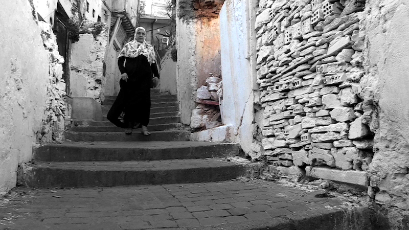 Ro caminal fotograma en blanco y negro de callejón de Argel con una señora con atuendo arabe