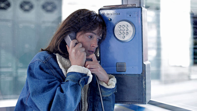 Patria: una chica habla por teléfono en una cabina.