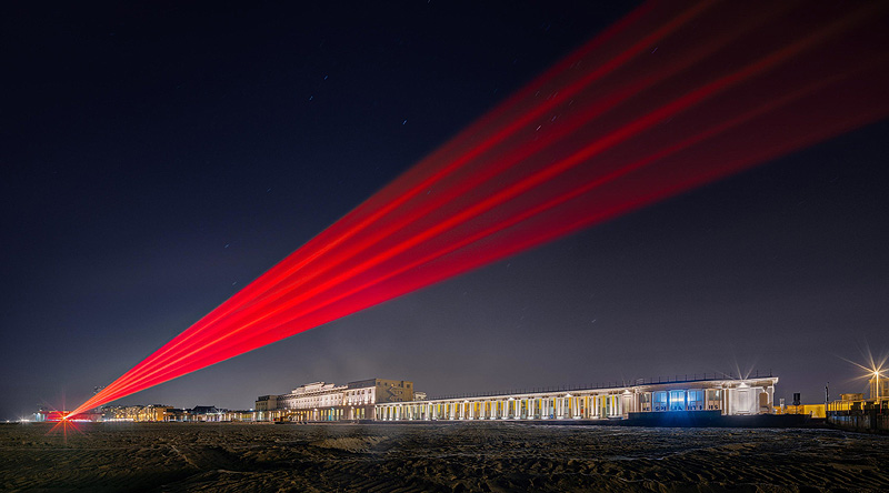 SpY_artista urbano. 5 haces de laser rojo en una playa por la noche 