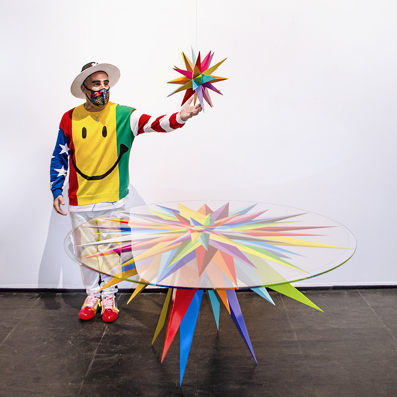 objetos con arte - Okuda posa junto a una mesa diseñada por él