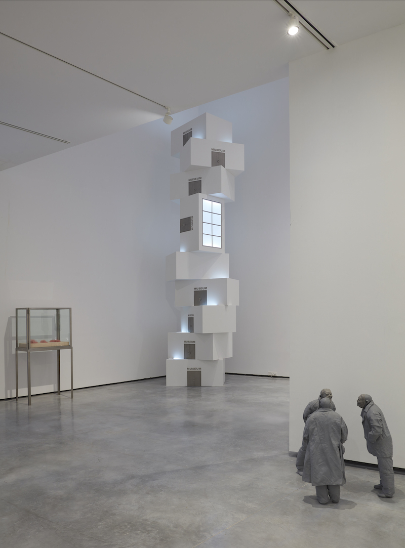 Museo Helga de Alvear en Cáceres, una sala con con 2 esculturas, una como una torre blanca y otra de tres hombres grises charlando y una vitrina