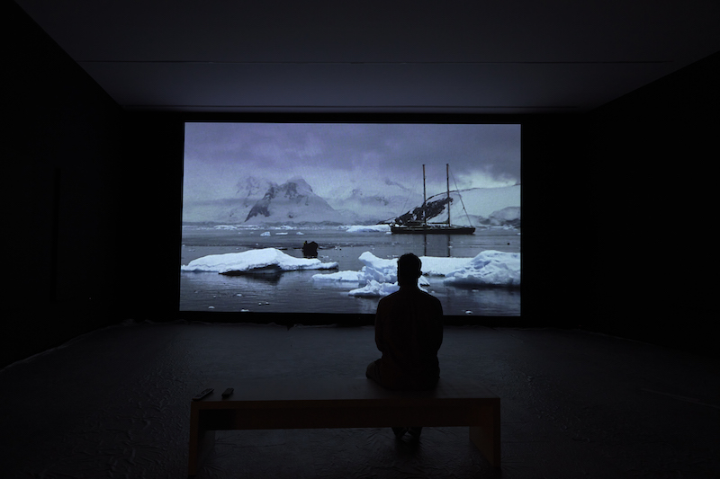 Museo Helga de Alvear en Cáceres, una sala con una proyección donde se ven bloques de hielo en el polo norte con un barco y un espectador mirando