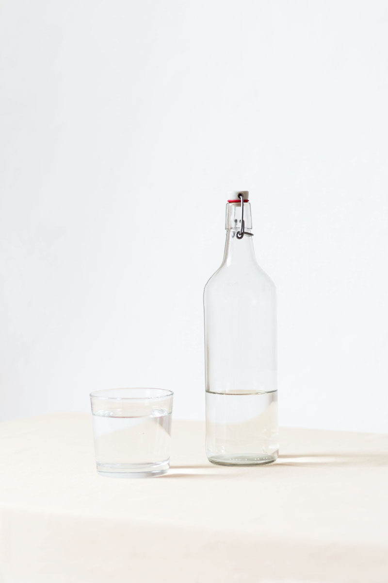 ¿Es obligatoria el agua del grifo gratis en los locales?: una botella y un vaso de cristal llenos de agua