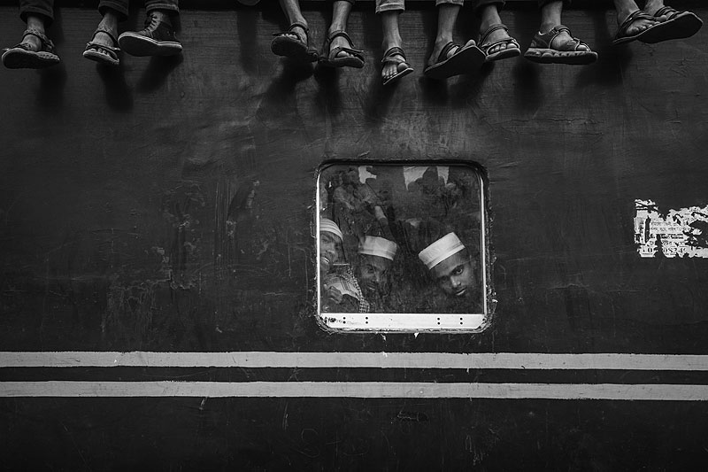 Festival Internacional de Fotografía de Castilla y León - foto en blanco y negro, vagón de tren, por la ventanilla se ven personajes árabes, del techo cuelgan pies de quienes van sentados sobre la parte superior