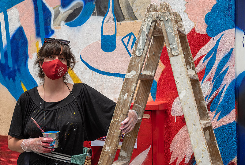 premio Alhambra CALLE 2021. LA artista Libertad Ballester posando con mascarilla delante de un mural
