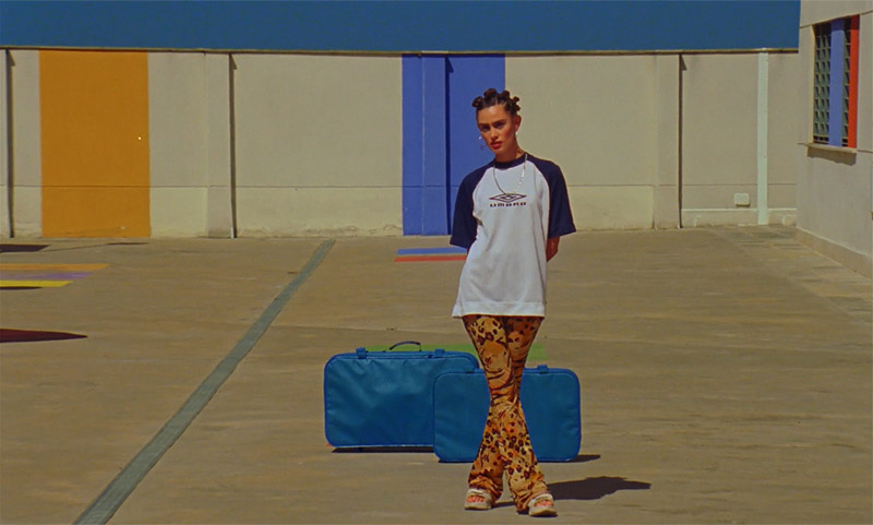 el amor amenazado - fotograma del corto, una chica esperando con maletas azules