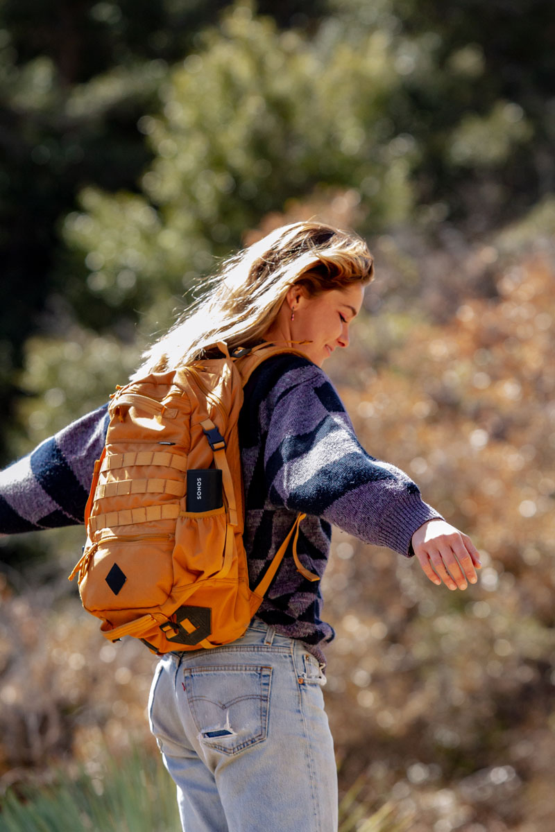 Sonos Roam altavoz: una chica en el campo con el gadget en la mochila