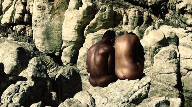 “Skins” video de Adrián Suárez- un cuerpo desnudo de chico negro en un paisaje costero con rocas