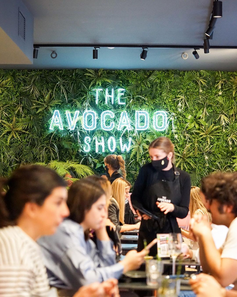 Mejores restaurantes vegetarianos en Madrid: interior de The Avocado Show, con Letras Luminosas con luces LED que indican el nombre del local