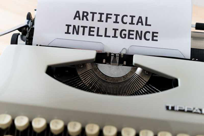 Inteligencia artificial qué es y cómo funciona: maquina de escribir con un papel donde se lee: Artificial Intelligence
