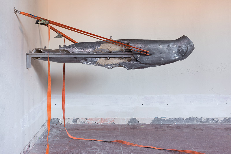 Exposiciones en el CA2M - vista de la exposición, una escultura hecha con desechos industriales sujeta en una pared