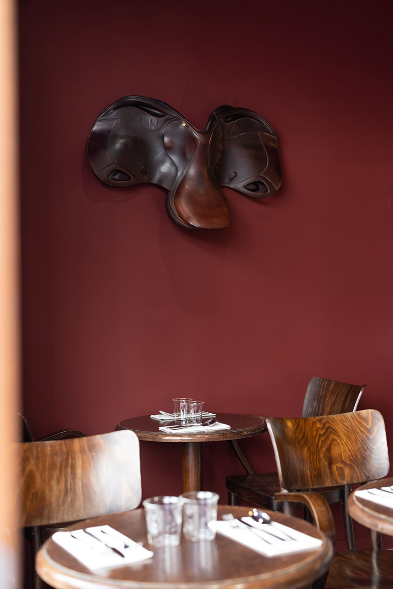 Restaurante Cavalier: la barra y la mesas altas. mesas de madera redondas tipo café y una pared en rojo granate