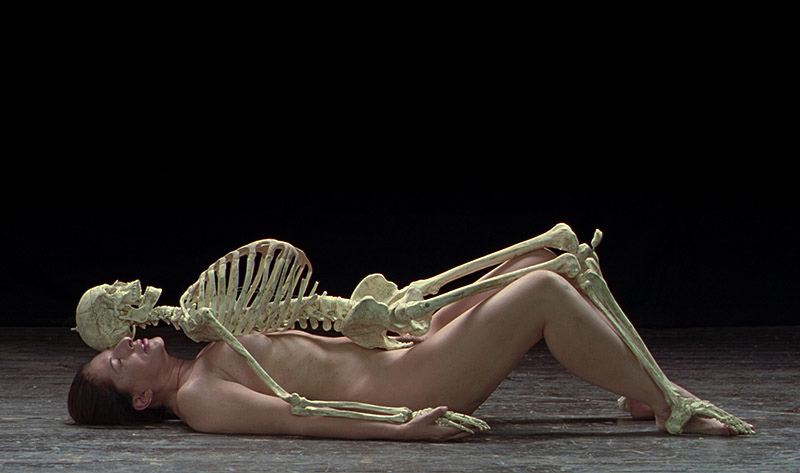 Marina Abramovic - performance de la artista, se la ve tumbada en el suelo desnuda con un esqueleto encima