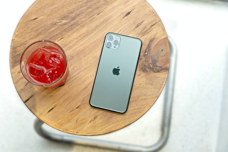 iOS 17: imagen de un iPhone 15 sobre una mesa junto a una bebida.
