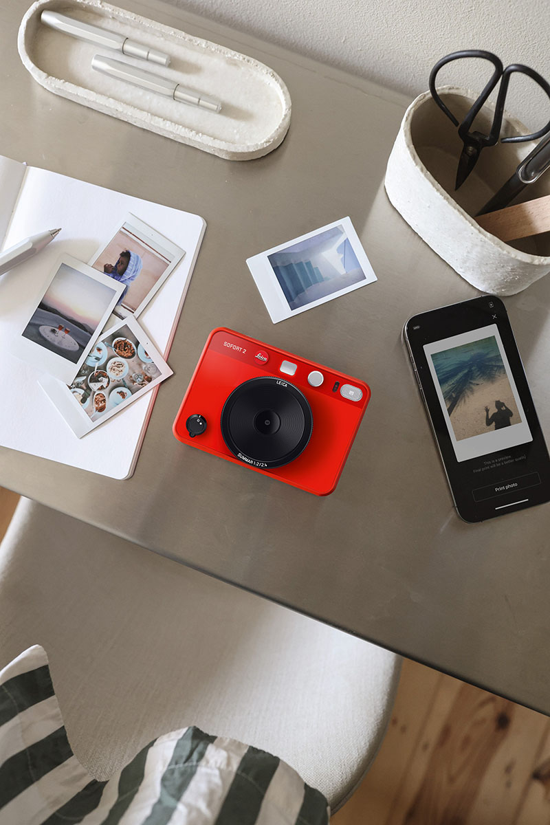 Leica Sofort 2: fotografía de la nueva cámara de Leica de color rojo rodeada de otros objetos.