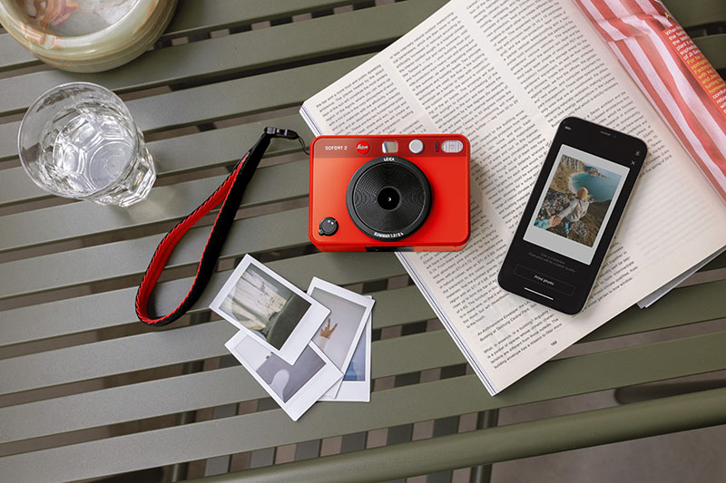 Leica Sofort 2: fotografía de la nueva cámara de Leica de color rojo rodeada de otros objetos.
