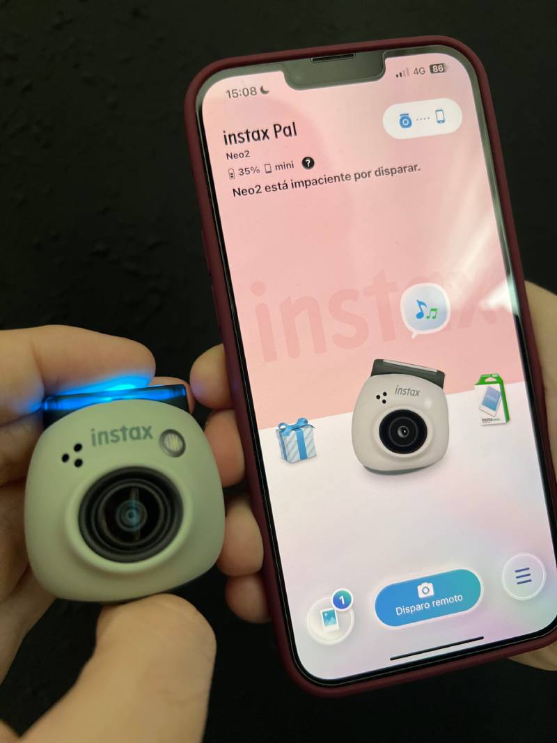 Instax Pal: la cámara Instax Pal encendida junto a un smartphone que muestra la aplicación.