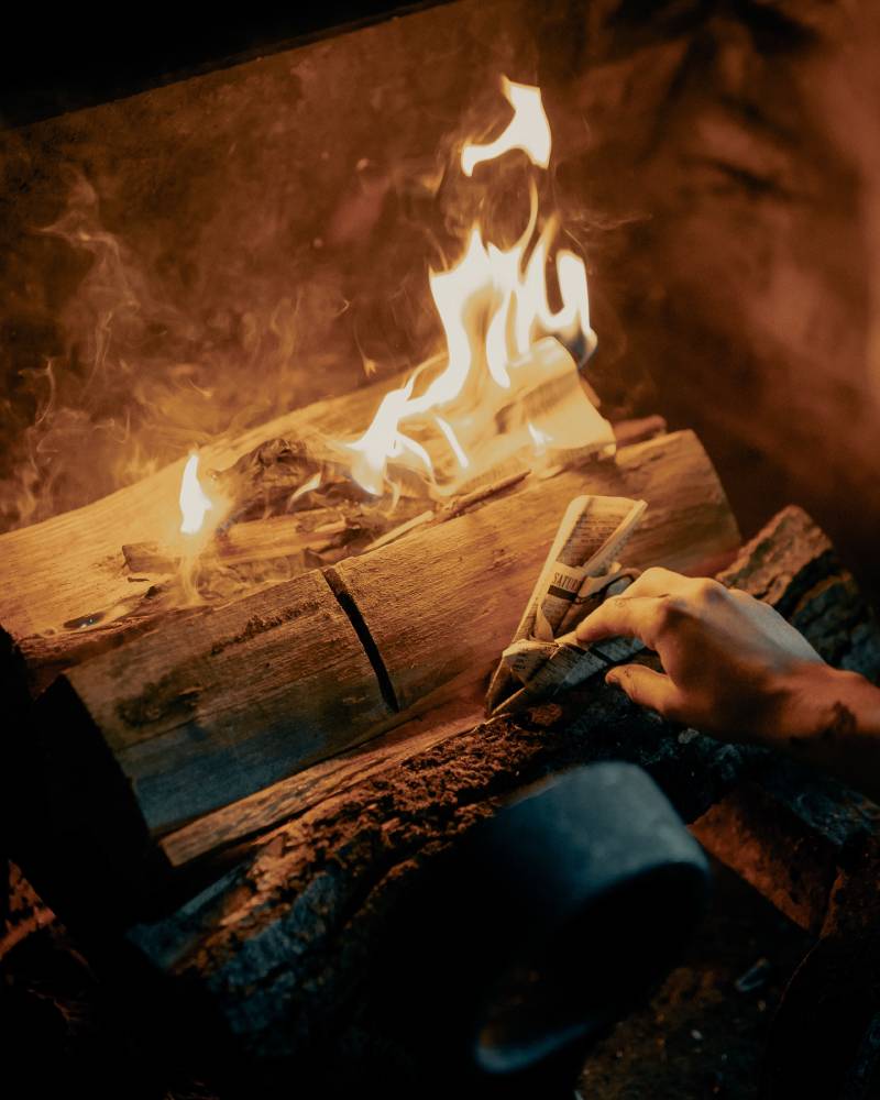Calefacción: fotografía de un hombre echando papel al fuego.