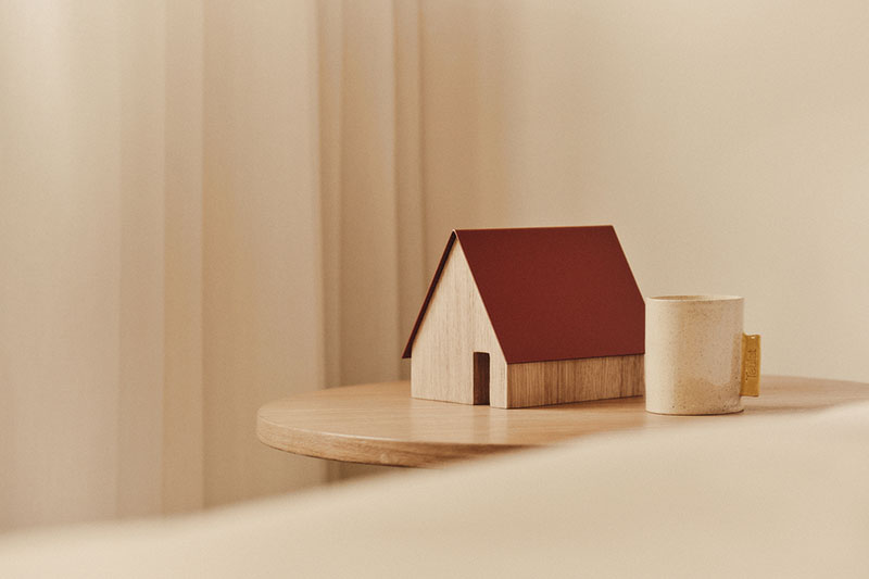 Teulat Editions: una casita de madera con el tejado rojo al lado de un taza de café