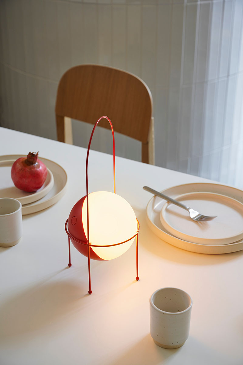 Lámpara Madco de Elisa Ossino para Ambientec: la pieza en color rojo sobre una mesa de comedor