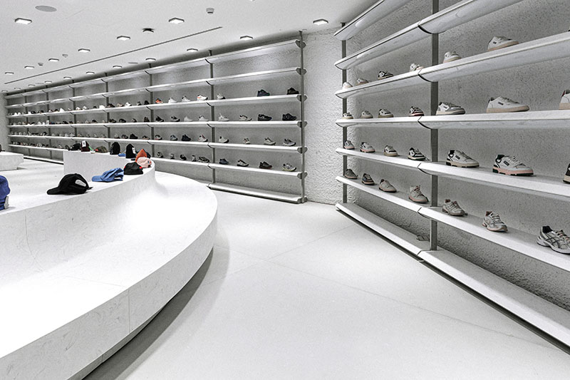 Wow Concept diseño espacial de Culdesac: zona de venta de zapatillas con un gran banco de cemento blanco redondo