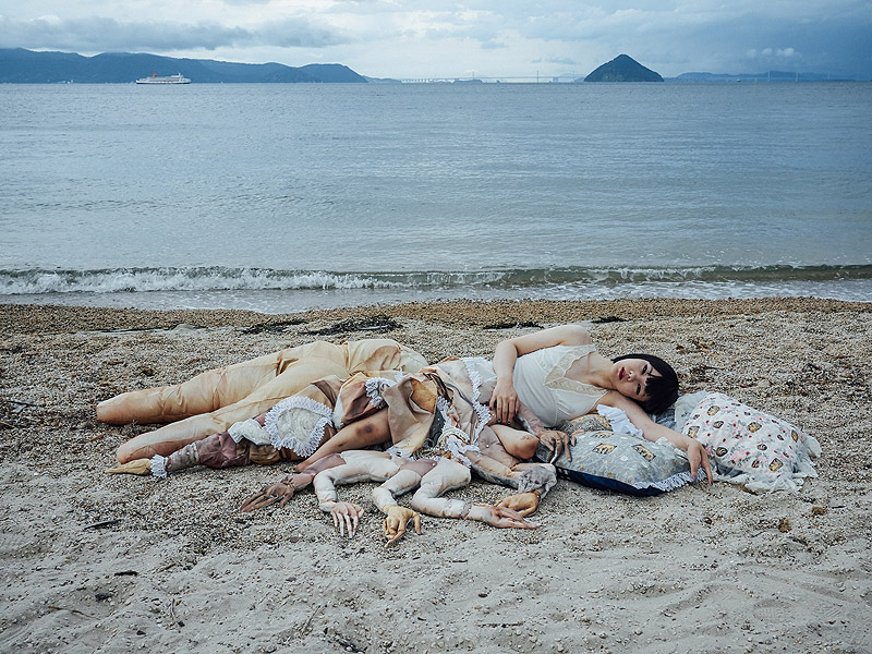 "Loving the Alien". Imagen de mujer con numerosas extremidades tumbada en la orilla de la playa.