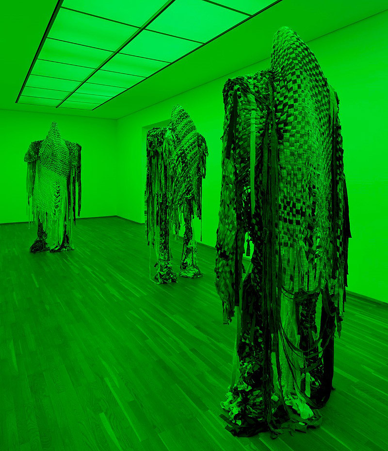 "Loving the Alien". Vista de la exposición con trajes colgados e iluminación verde.