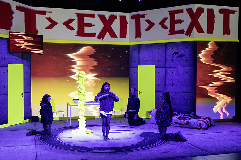 Angela (a strange loop) - representación teatral con personajes y un escenario con pantallas de video y colores fluorescentes