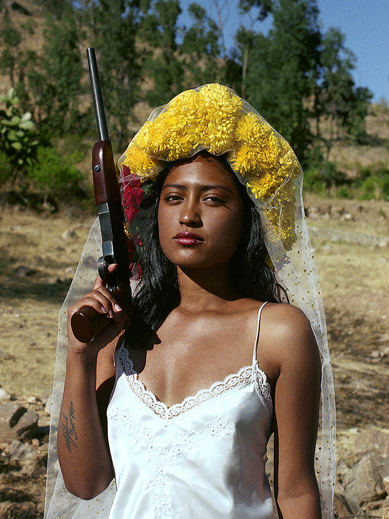Foam Talent. Imagen de un mujer con corona de flores y una pistola.