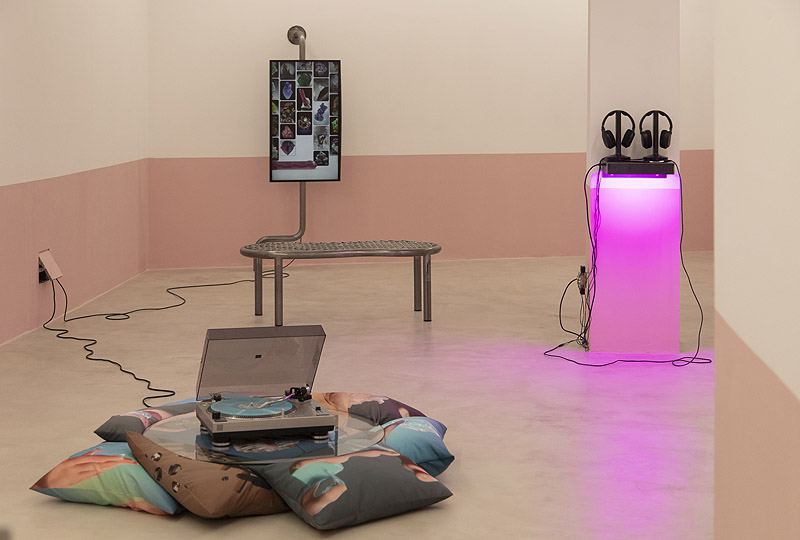 Sarah & Charles - instalación artística con un tocadiscos, un vinilo coloreado, cojines, una pantalla y una estructura metálica