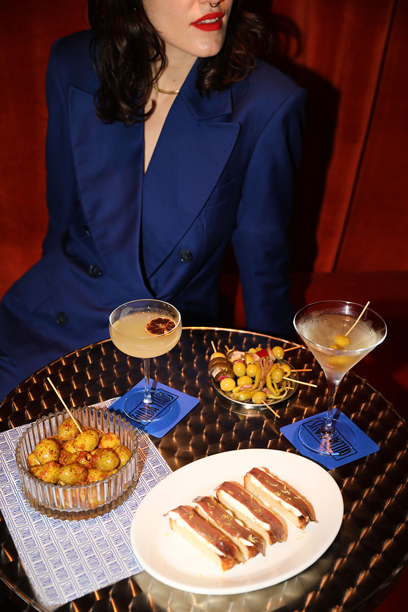 Gilda Haus Bar: una zona del local, una chica con un traje azul con una mesa llena de comida