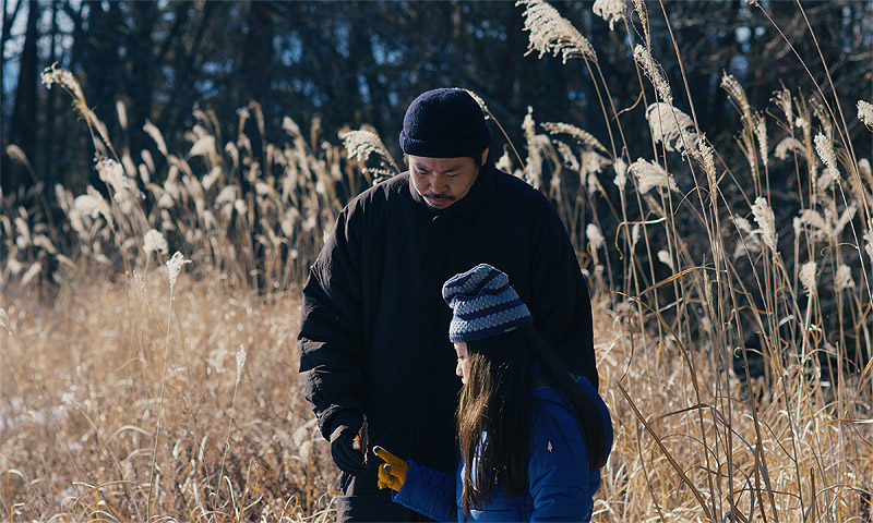 El mal no existe - Fotograma de la película, se ve a un hombre y una niña en un bosque nevado