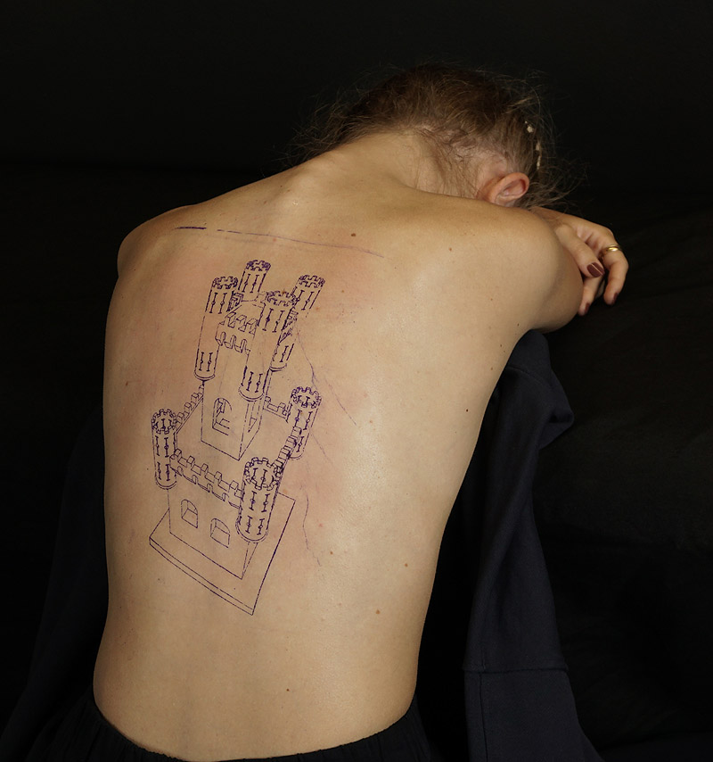 Estibaliz Sadaba - (Re)construcciones - imagen de espalda de mujer con un edificio antiguo tatuado