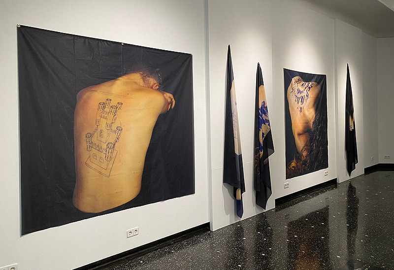 Estibaliz Sadaba - (Re)construcciones - imagen de esposición con fotografías de espaldas de mujerer con un edificio antiguo tatuado