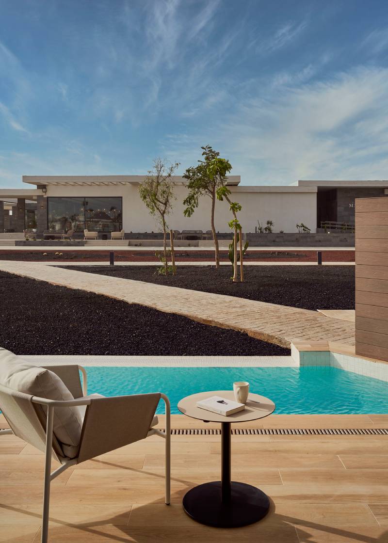Barceló Playa Blanca: Terraza de la piscina con una silla y una mesa y el edificio de fondo