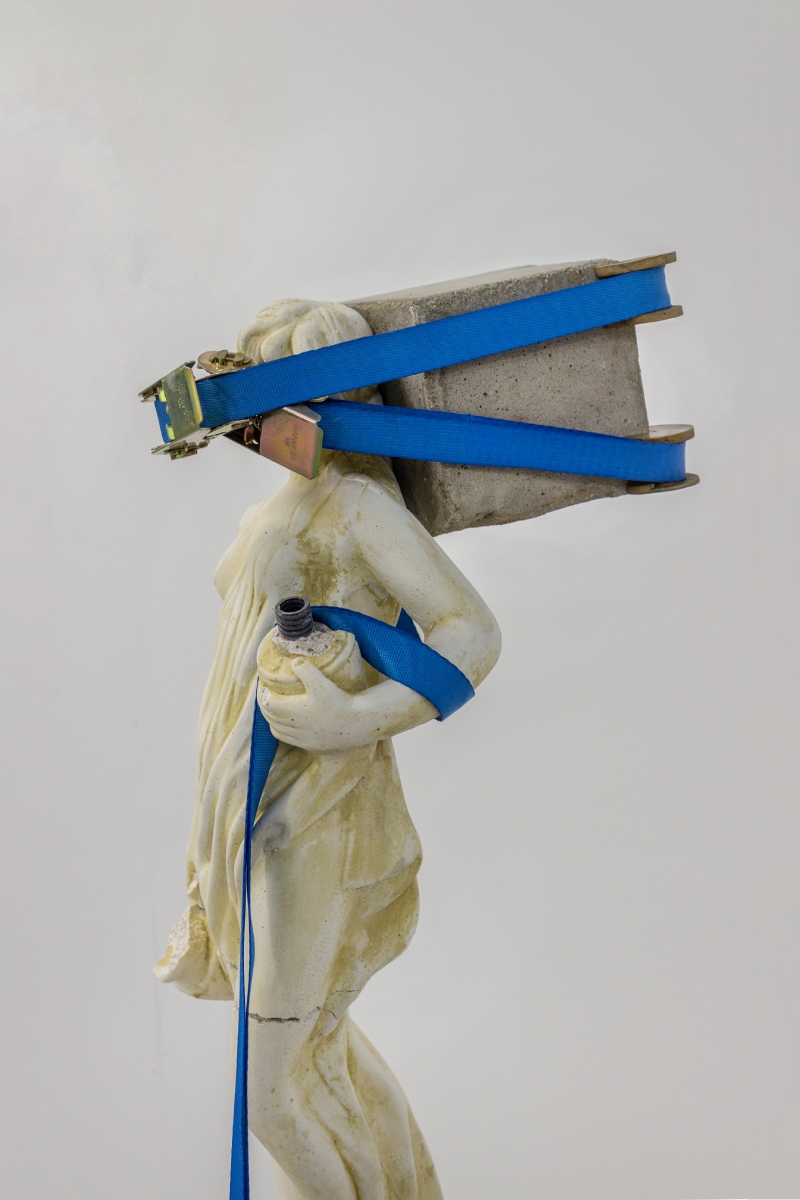 Leo Fourdrinier. Imagen de una escultura clásica cargando una piedra atada con un cinturón.