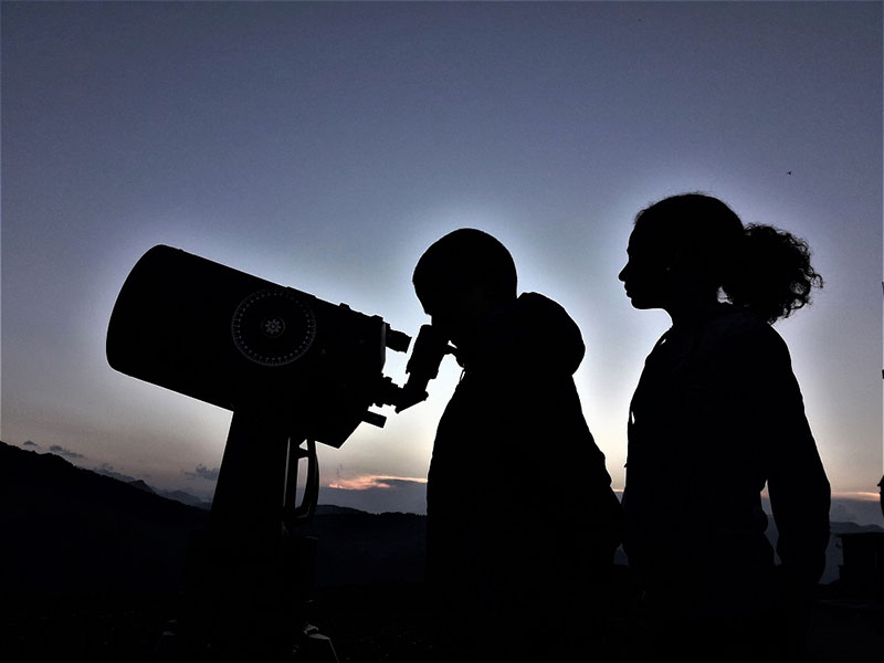 Planes nocturnos Paradores: dos personas mirando las estrellas con telescopio