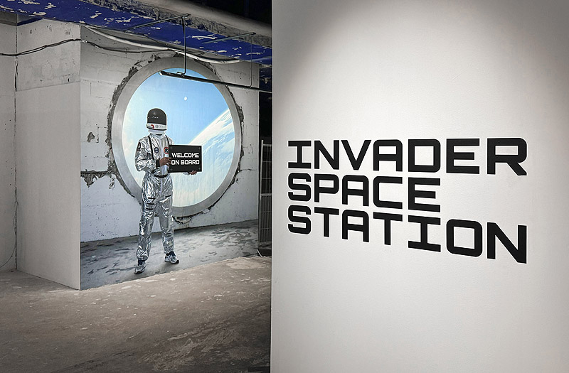 Invader - imagen de la exposición "Invader Space Station" con gente viendo las obras
