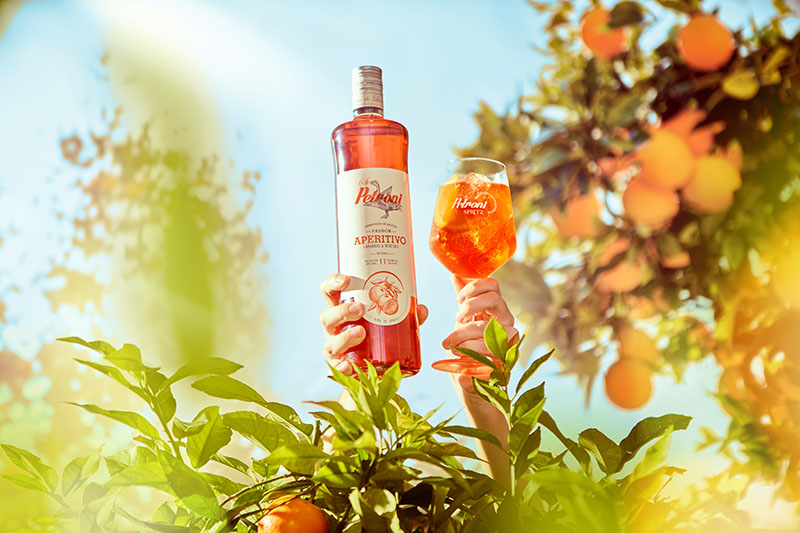 St Petroni Aperitivo Spritz: la botella junto a una copa entre naranjos