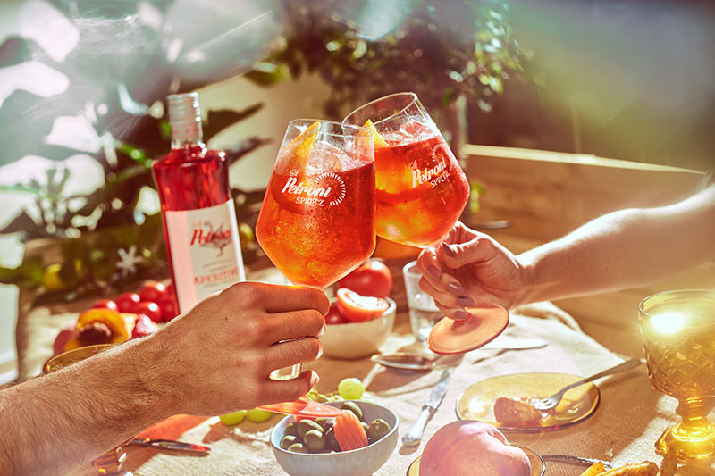 St Petroni Aperitivo Spritz: un grupo de amigos brindando con una botella de este aperitivo al lado