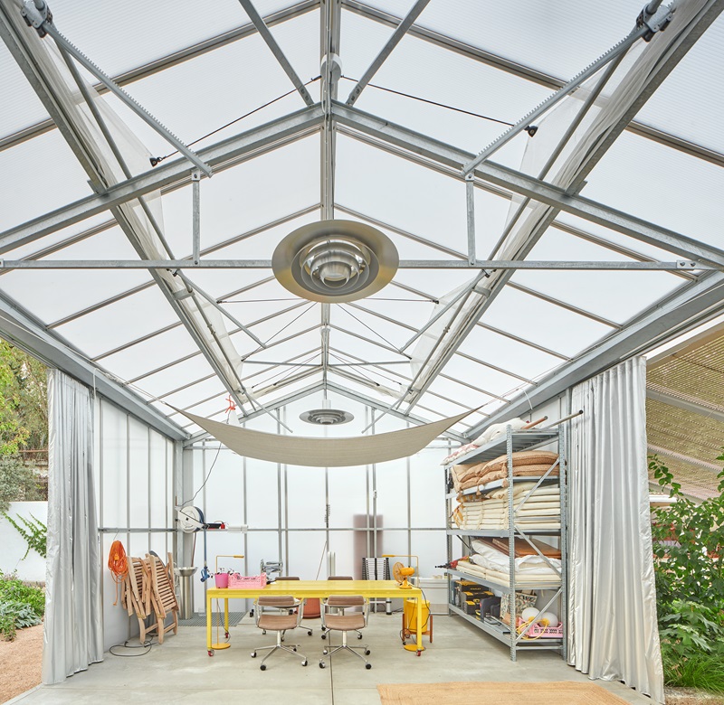 Kresta-Garden-House: interior del invernadero con mesa amarilla 