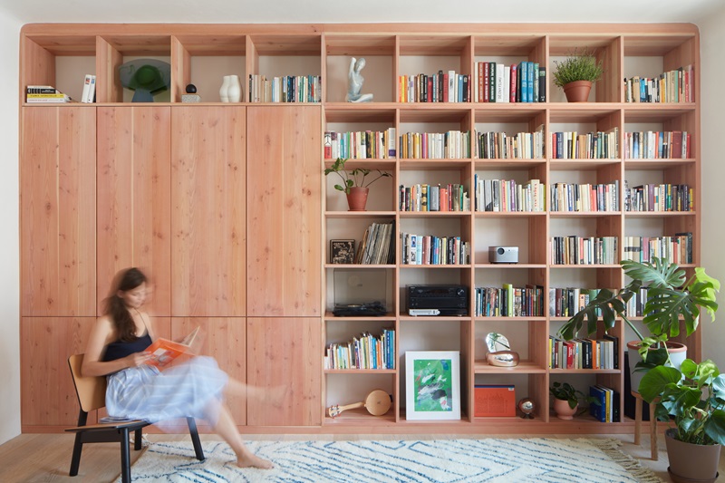 Plus-One-Architects- Vršovice-Apartment: estantería de madera con libros en el salón